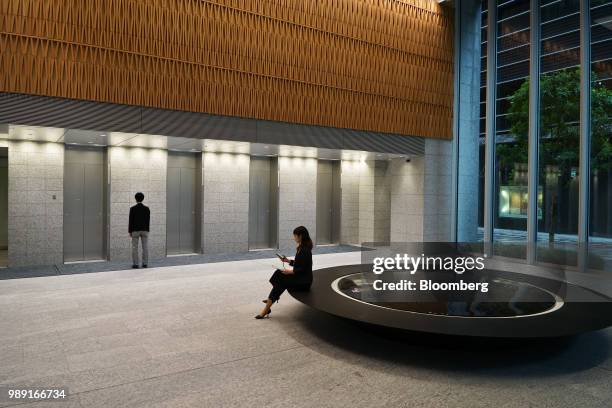 Woman sits at the entrance hall of Takeda Pharmaceutical Co.'s global headquarters in Tokyo, Japan, on Monday, June 11, 2018. Melding futuristic...