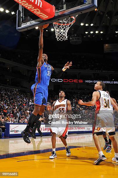 Kevin Durant of the Oklahoma City Thunder shoots a layup against Reggie Williams and Stephen Curry of the Golden State Warriors during the game at...