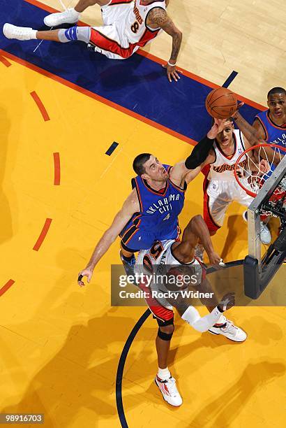 Nick Collison of the Oklahoma City Thunder goes up for a rebound against Corey Maggette and Stephen Curry of the Golden State Warriors during the...