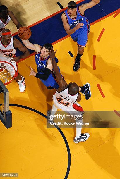 Nick Collison of the Oklahoma City Thunder shoots a layup against Corey Maggette and Anthony Tolliver of the Golden State Warriors during the game at...