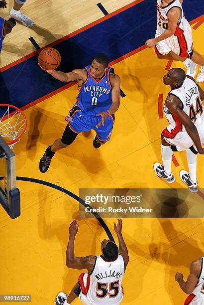 Russell Westbrook of the Oklahoma City Thunder shoots a layup against Stephen Curry, Anthony Tolliver and Reggie Williams of the Golden State...