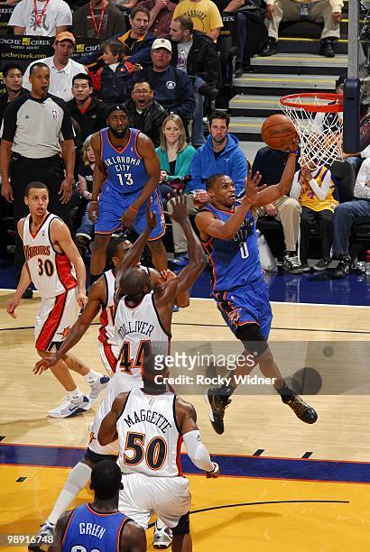 Russell Westbrook of the Oklahoma City Thunder shoots a layup against Anthony Tolliver and Corey Maggette of the Golden State Warriors during the...