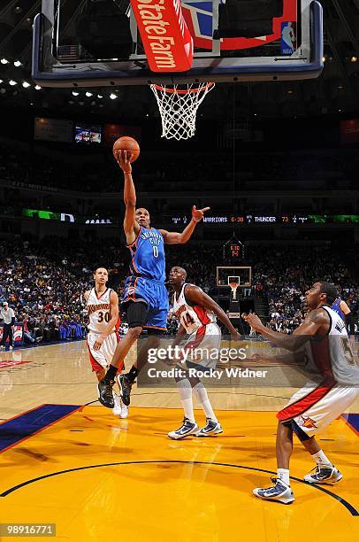 Russell Westbrook of the Oklahoma City Thunder shoots a layup against Stephen Curry, Anthony Tolliver and Reggie Williams of the Golden State...