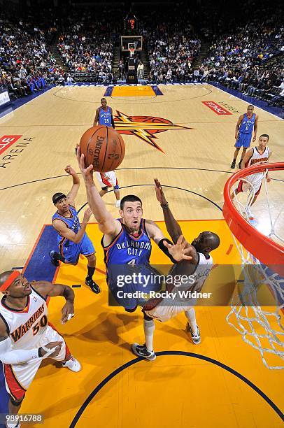 Nick Collison of the Oklahoma City Thunder shoots a layup against Corey Maggette and Anthony Tolliver of the Golden State Warriors during the game at...