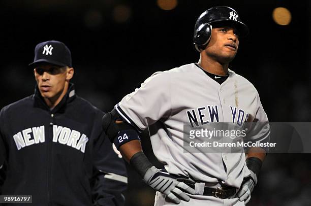 Robinson Cano of the New York Yankees is looked after by manager Joe Girardi after being hit by a pitch in the sixth inning against the Boston Red...
