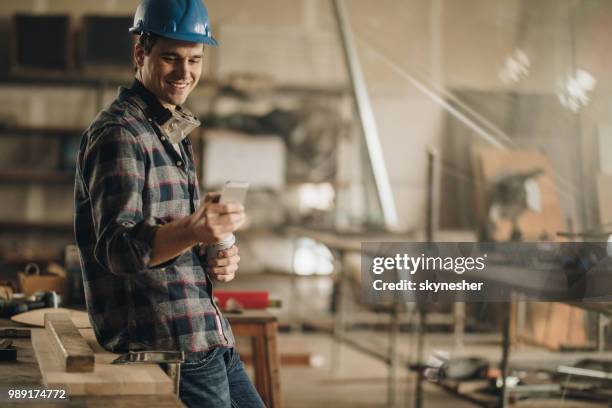 happy manual worker using cell phone on coffee break in a workshop. - 2017 common good forum stock pictures, royalty-free photos & images