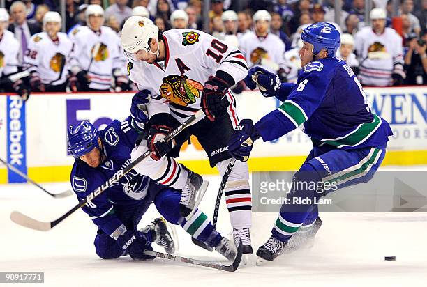 Patrick Sharp of the Chicago Blackhawks looses the puck while trying to slip between Ryan Johnson and Sami Salo of the Vancouver Canucks during the...