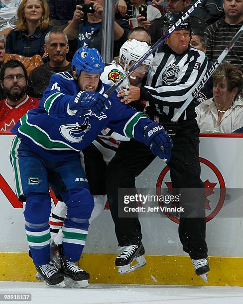 Tanner Glass of the Vancouver Canucks checks Patrick Kane of the Chicago Blackhawks into Linesmen Jay Sharrers in Game Four of the Western Conference...