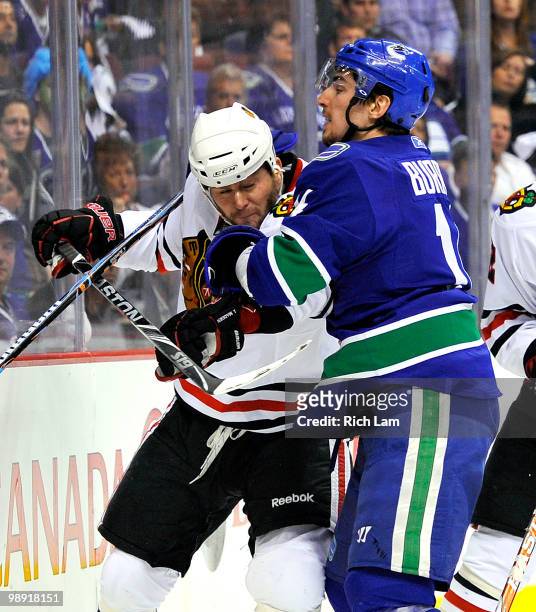 Alex Burrows of the Vancouver Canucks grabs a hold of John Madden of the Chicago Blackhawks while battling behind the net during the third period in...