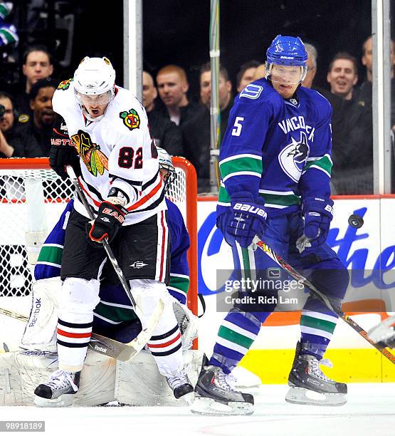 Christian Ehrhoff of the Vancouver Canucks and Tomas Kopecky of the Chicago Blackhawks react as a puck is shot towards them while standing in front...