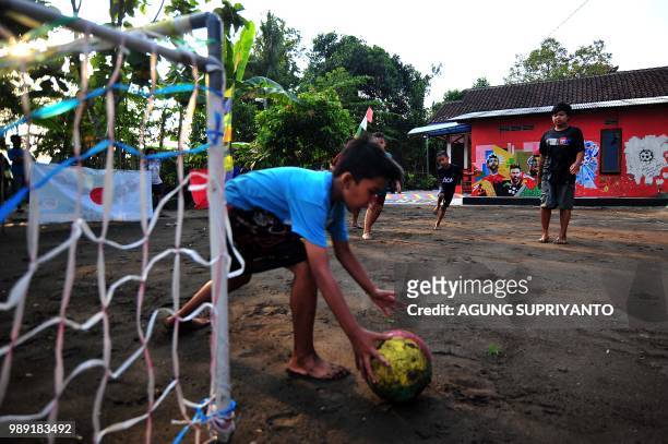 This picture taken in Tegalrejo, Yogyakarta on July 1, 2018 shows young boys playing football near a FIFA World Cup 2018 theme.
