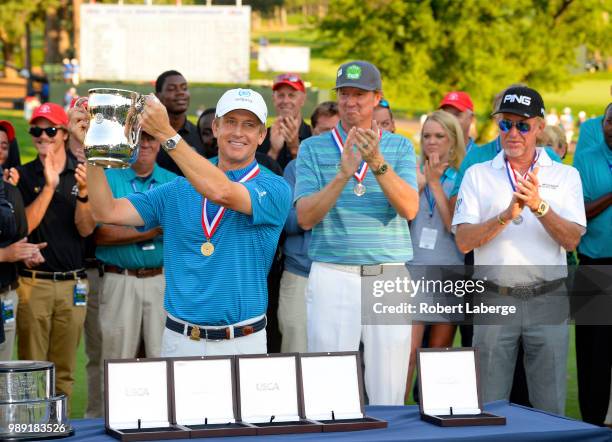 David Toms lifts the winner's trophy as Tim Patrovic, Miguel Angel Jimenez of Spain look on during the final round of the U.S. Senior Open...