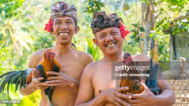 two men are smiling at the camera. bali,indonesia - man holding chicken wing stock pictures, royalty-free photos & images