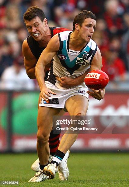 Travis Boak of the Power handballs whilst being tackled by David Hille of the Bombers during the round seven AFL match between the Essendon Bombers...