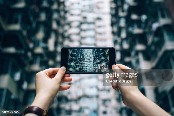 human hands photographing the facade of old and high density residential blocks with smartphone in city - solo 2018 film foto e immagini stock