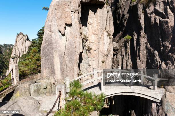 small arch bridge spanning deep canyon of granite rocks, mount huangshan, huang shan, anhui province, china - inspanning stock pictures, royalty-free photos & images