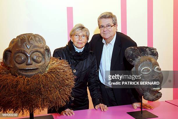 Patrick and Catherine Sargos pose next to masks and sculptures displayed during an exhibition on "Africa, Arts and Traditions from profane to...