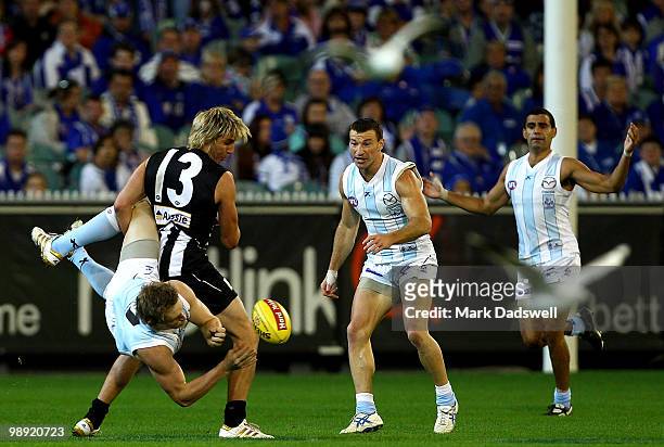 Jack Ziebell of the Kangaroos handballs as he is tackled by Dale Thomas of the Magpies during the round seven AFL match between the Collingwood...