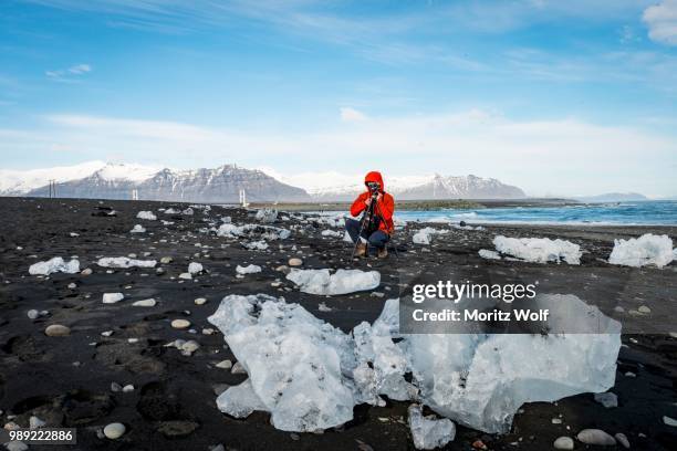 tourist takes photos of ice floes on black lava beach, diamond beach, fjallsarlon glacier lagoon, east iceland, iceland - austurland stock pictures, royalty-free photos & images