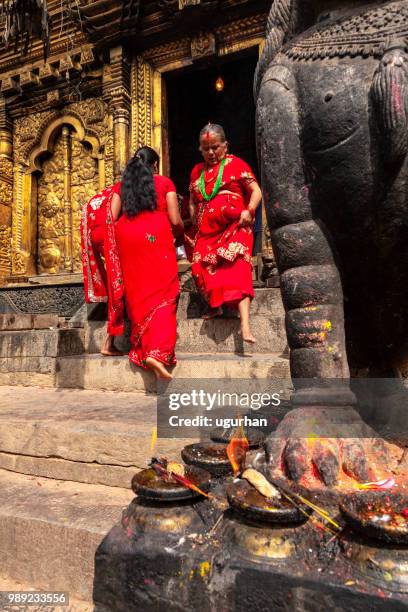 nepalese women clad in red traditional clothing in temple. - clad stock pictures, royalty-free photos & images