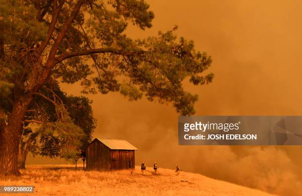 Firefighters watch as flames from the County Fire climb a hillside in Guinda, California, on July 1, 2018. Californian authorities have issued red...
