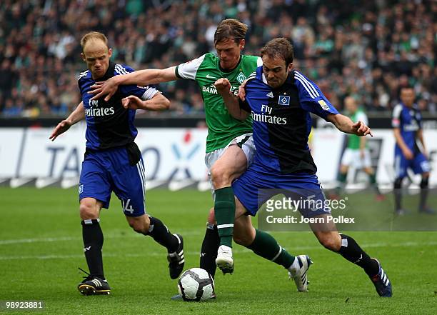 Joris Mathijsen and David Jarolim of Hamburg and Tim Borowski of Bremen battle for the ball during the Bundesliga match between SV Werder Bremen and...