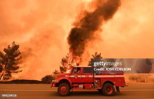 Firefighters work to control a fire as flames from the County Fire jump across Highway 20 near Clearlake Oaks, California, on July 1, 2018. -...