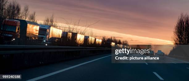 Row of trucks push through a traffic jam during sunrise on the motorway A2, headed towards Berlin and Hanover, near Lehrte, Germany, 18 December...