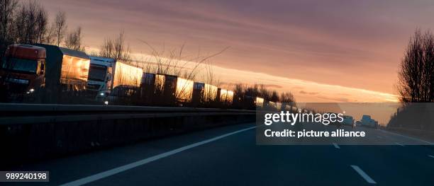 Dpatop - A row of trucks push through a traffic jam during sunrise on the motorway A2, headed towards Berlin and Hanover, near Lehrte, Germany, 18...