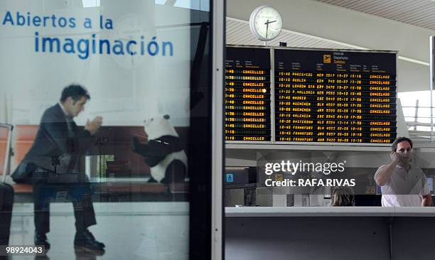 Passenger talks on his phone in front of a departure board displaying cancelled flights from Bilbao's airport in Loiu, northern Spain, on May 8,...