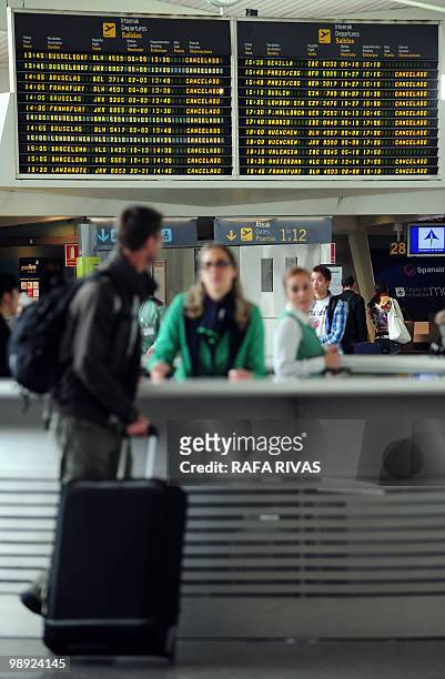 Passenger stands next to the information point in front of a departure board displaying cancelled flights at Bilbao's airport in Loiu, northern...