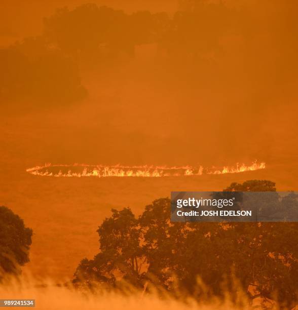 Ring of fire started by embers expands before passing through a property as the County Fire burns in Guinda, California on July 1, 2018. -...