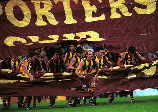 Hawthorn players run thru the banner at the start of the game against Brisbane during the round 13 AFL match between the Brisbane Lions and the...