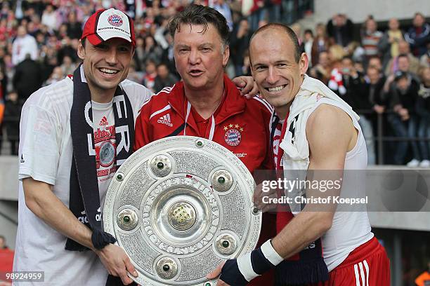 Mark van Bommel, head coach Louis van Gaal and Arjen Robben of Bayern present the German Championship trophy during the Bundesliga match between...