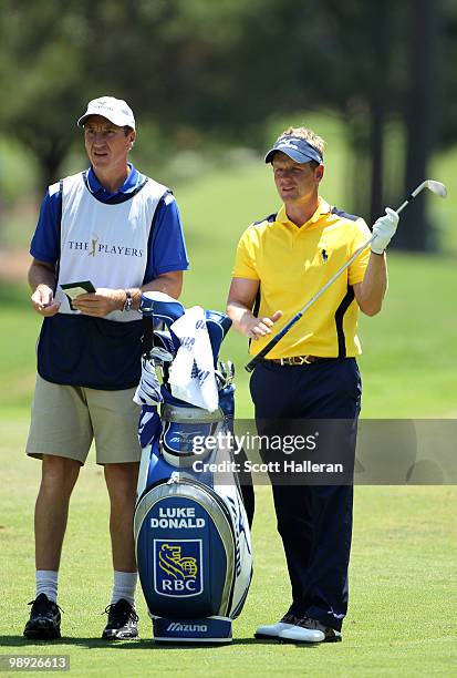 Luke Donald of England talks with caddie John McLaren before playing a fairway shot on the first hole during the third round of THE PLAYERS...