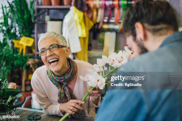 florist laughing with a customer in a flower shop - florest stock pictures, royalty-free photos & images