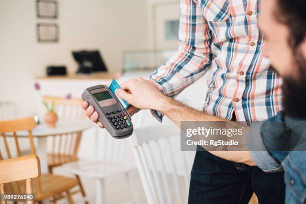 young man in a coffee shop using his credit card - earring card stock pictures, royalty-free photos & images