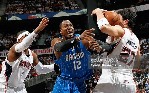 Josh Smith of the Atlanta Hawks defends as Zaza Pachulia fouls Dwight Howard of the Orlando Magic during Game Three of the Eastern Conference...