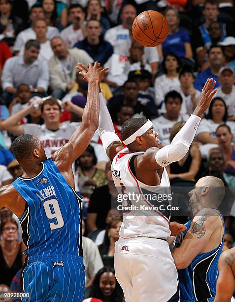 Josh Smith of the Atlanta Hawks loses the ball as he attacks the basket against Rashard Lewis and Marcin Gortat of the Orlando Magic during Game...