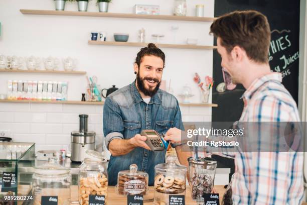 smiling sales man assisting customer in credit card purchase - feirante imagens e fotografias de stock