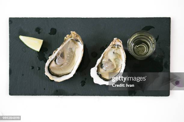 oysters on black stone plate with ice, white wine and lemon - ice wine stock pictures, royalty-free photos & images