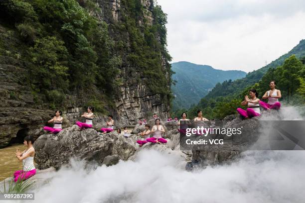 Yoga enthusiasts perform yoga for relaxation by a stream at the Three Gorges reservoir area on June 30, 2018 in Yichang, Hubei Province of China.