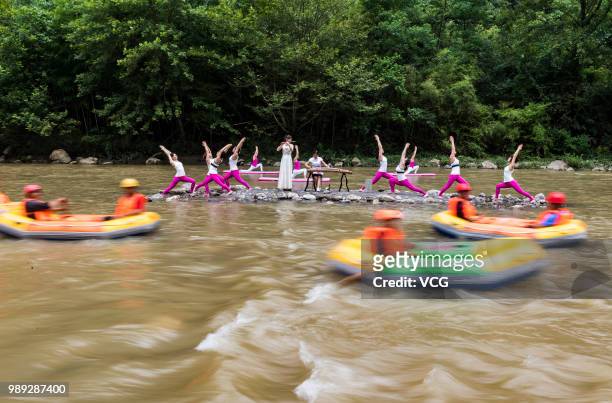 Yoga enthusiasts perform yoga for relaxation by a stream at the Three Gorges reservoir area on June 30, 2018 in Yichang, Hubei Province of China.