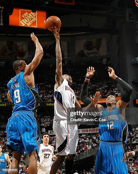 Jamal Crawford of the Atlanta Hawks drives between Rashard Lewis and Dwight Howard of the Orlando Magic during Game Three of the Eastern Conference...