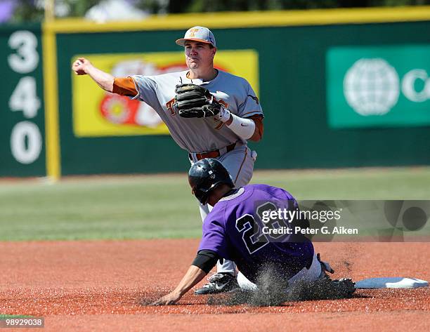 Second baseman Jordan Etier of the Texas Longhorns turns a double play with a throw over baserunner Nick Martini of the Kansas State Wildcats during...