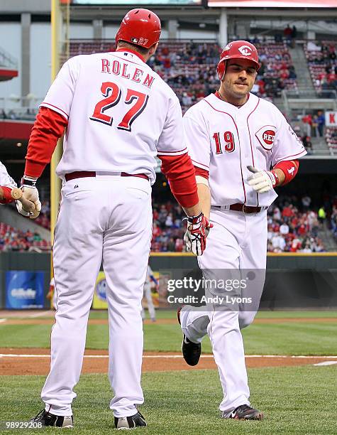 Joey Votto of the Cincinnati Reds is congratulated by Scott Rolen after scoring a run in the first inning during the game against the Chicago Cubs...