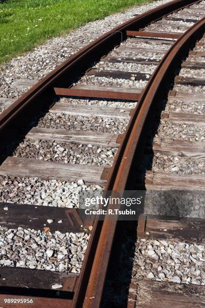 tram rail road track disappearing around a curve in grass - européen de lest photos et images de collection
