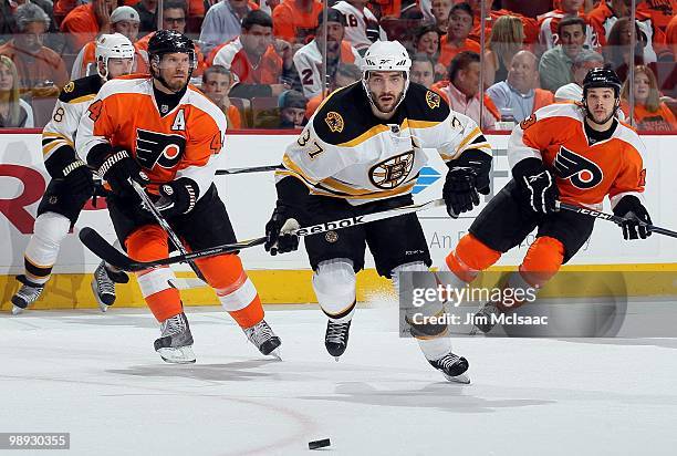 Patrice Bergeron of the Boston Bruins skates against Kimmo Timonen and Daniel Carcillo of the Philadelphia Flyers in Game Three of the Eastern...