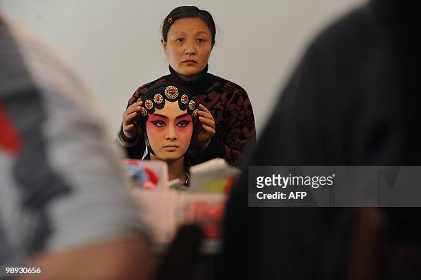Young Chinese opera performer from the Anhui art college has her costume fitted as she prepares for a Peking Opera performance at their school in...