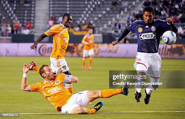 Brad Davis of Houston Dynamo kicks the ball past Dario Delgado of Chivas USA to score a goal as teammate Dominic Oduro looks on during first half...